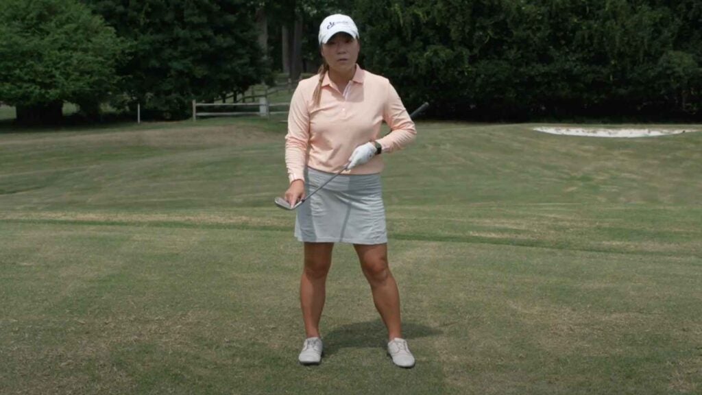 Golf Teacher Cathy Kim demonstrates a drill with four tees on golf course.