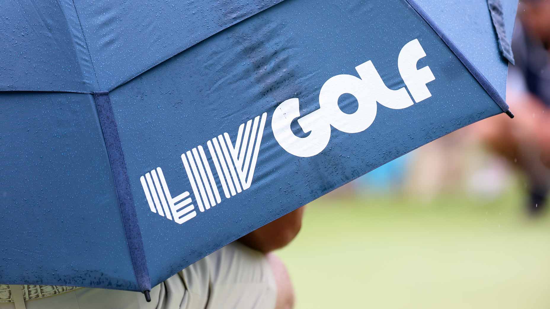 Fan holds umbrella with LIV Golf logo at the first hole during day one of the 2024 LIV Golf Greenbrier tournament at The Old White Course.