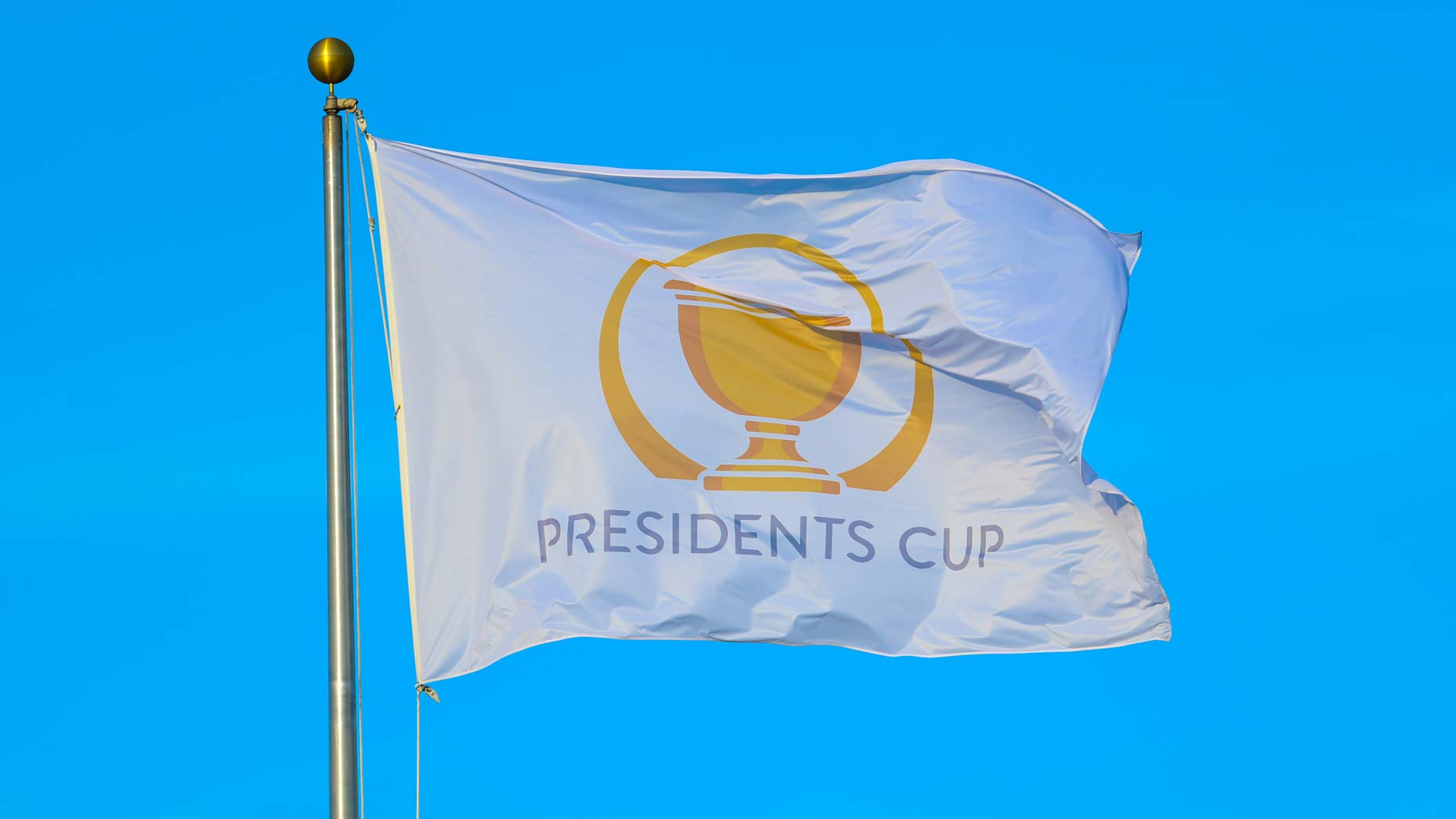 The flag of the President's Cup flutters in the wind against the blue sky.