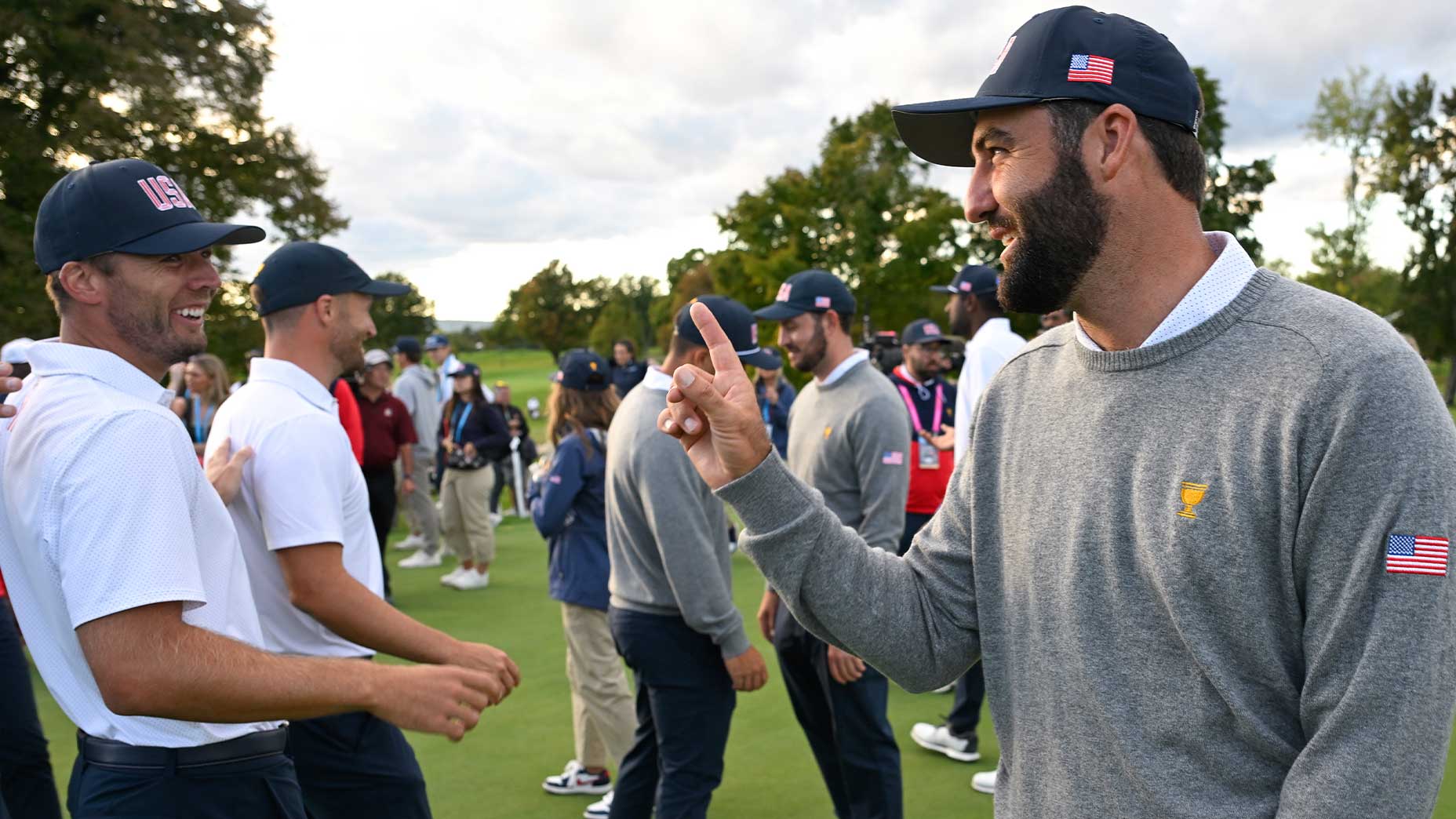 scottie scheffler raises his finger to Sam Burns in the president's trophy