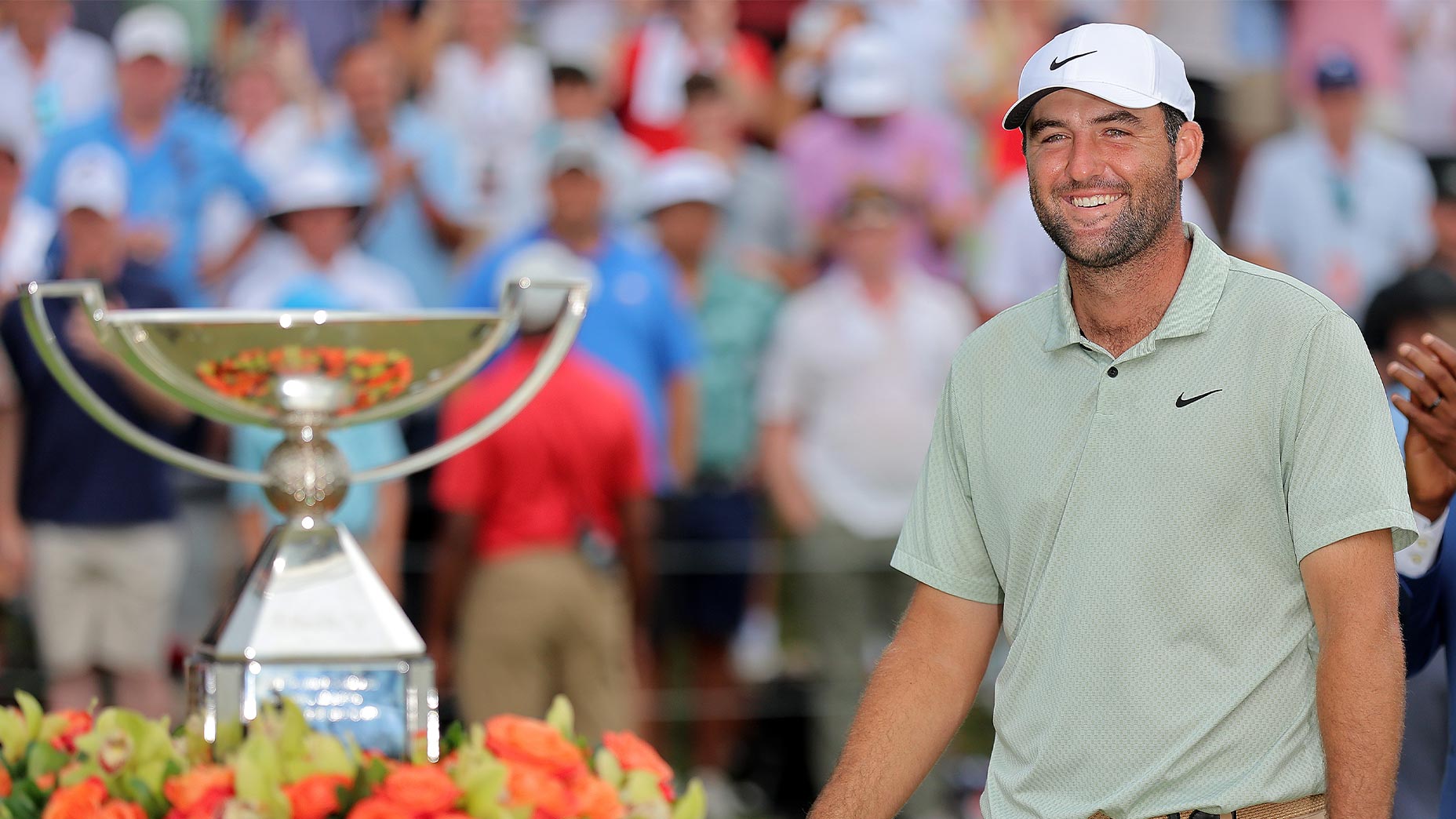 scotie scheffler smiles next to the tour championship trophy