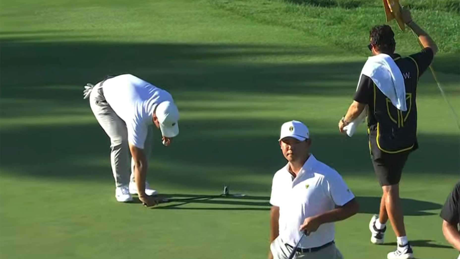 Tom Kim places his putter on the green.