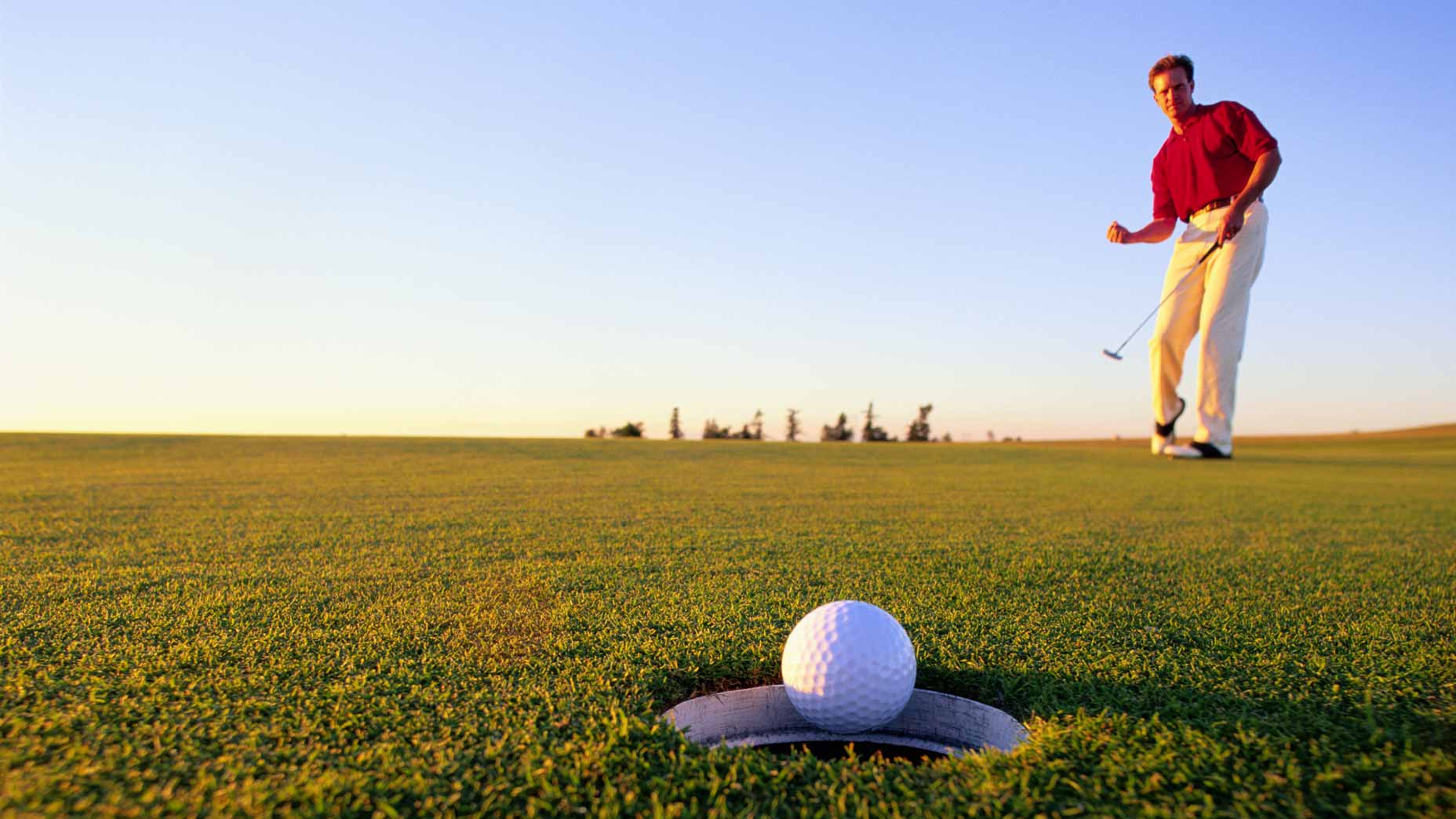 Golfer making a putt on a green.