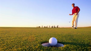 Golfer making a putt on a green.