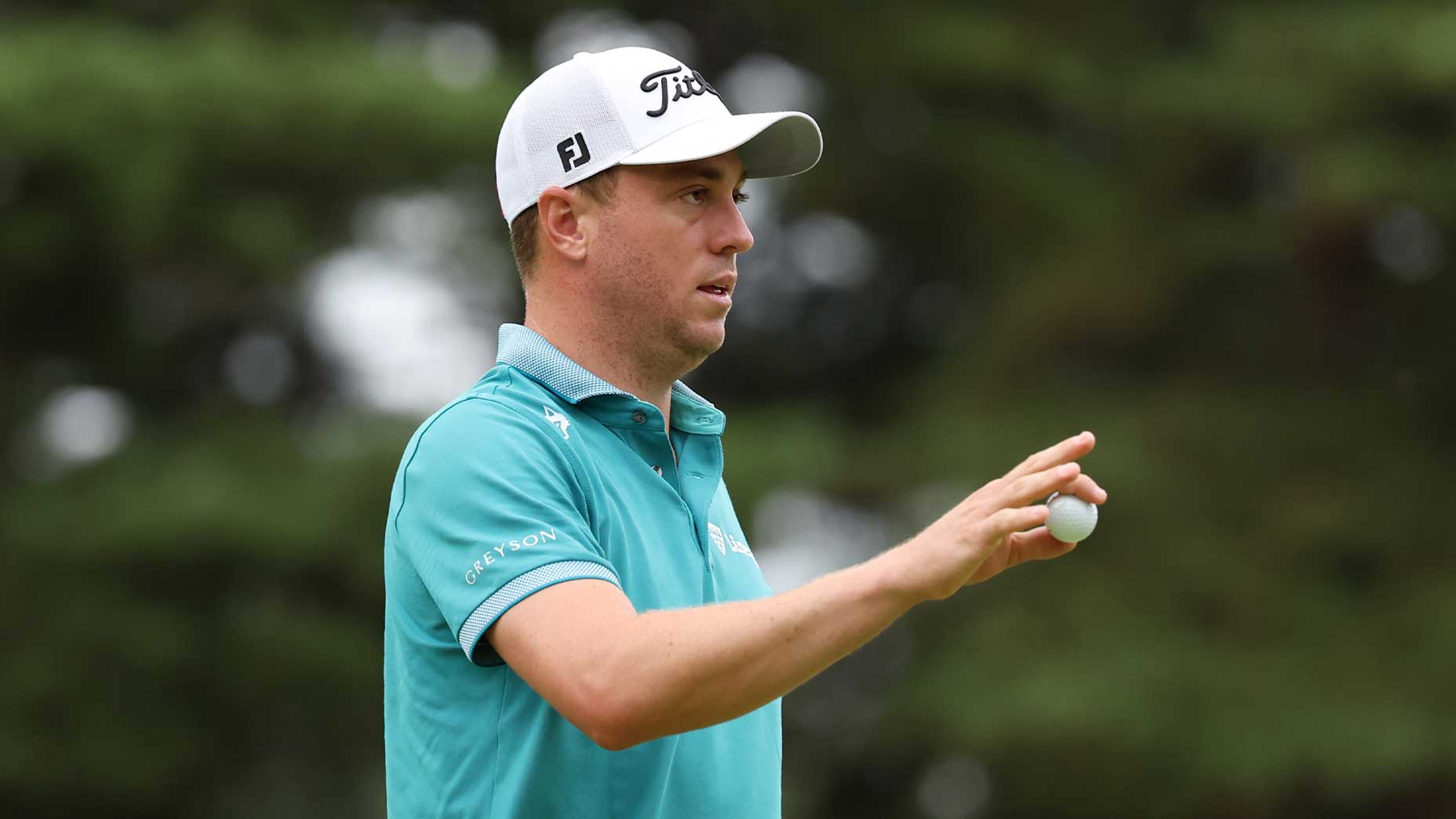 Justin Thomas extends his hand with a green t-shirt at the Zozo Championship