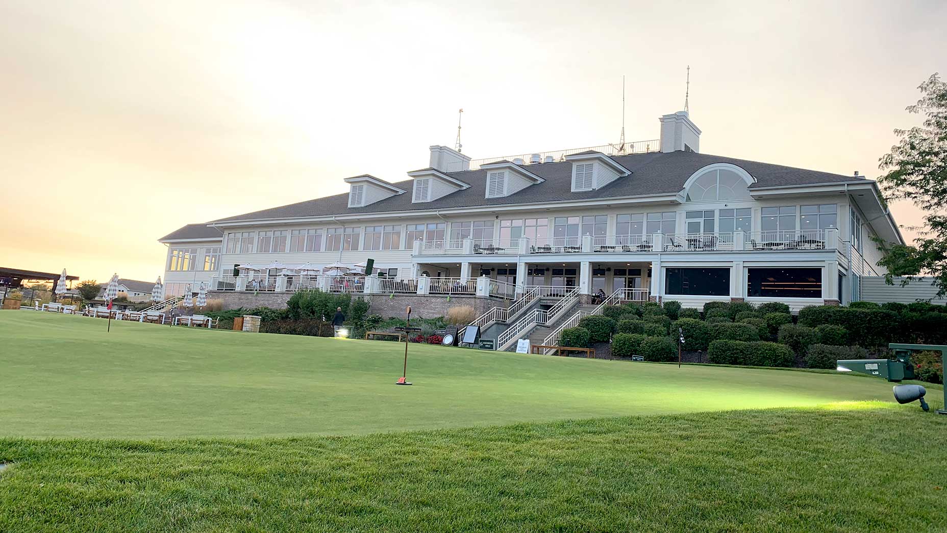 the putting green and clubhouse at destination geneva national