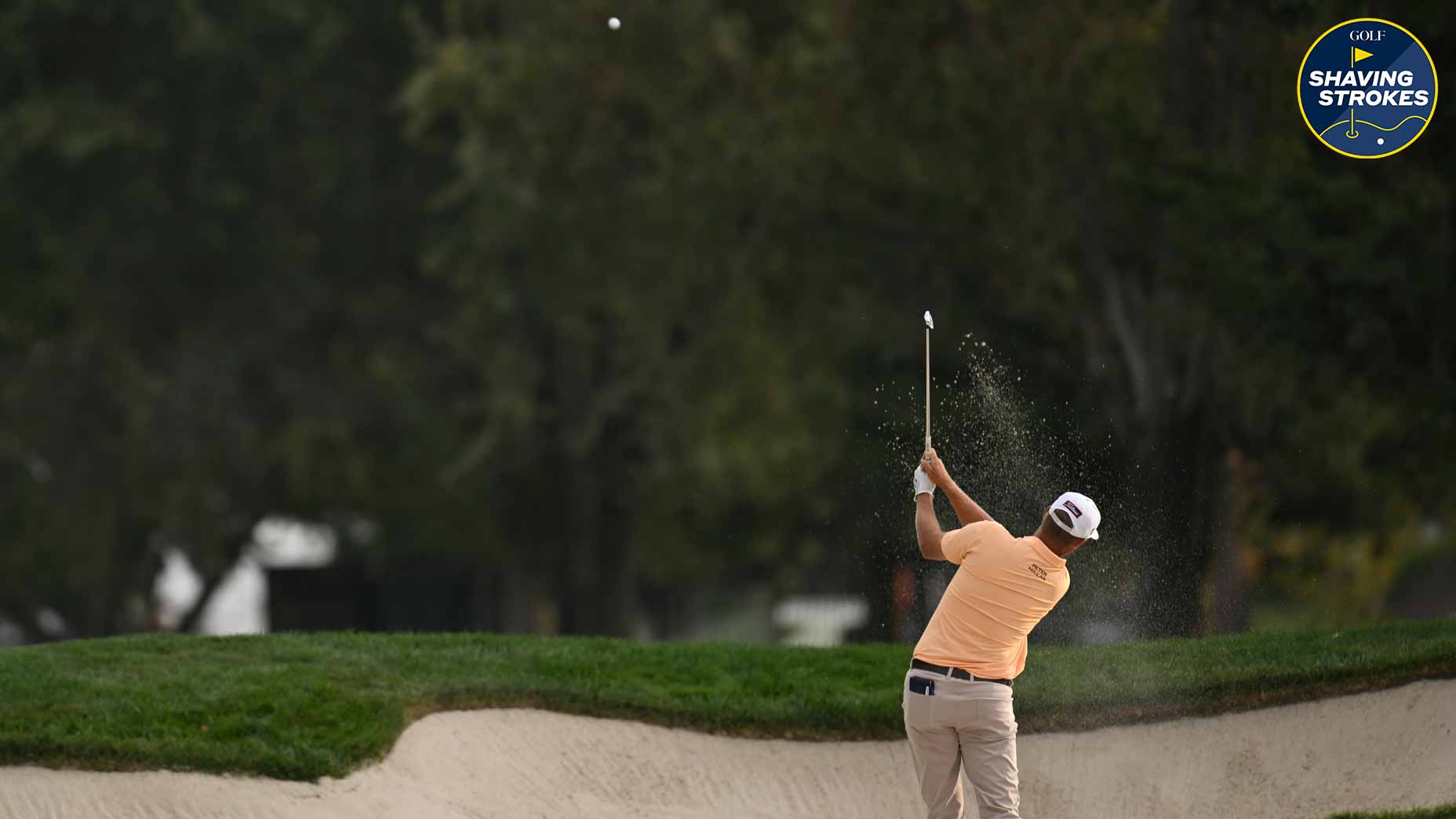 Golfer hits shot out of bunker on golf course