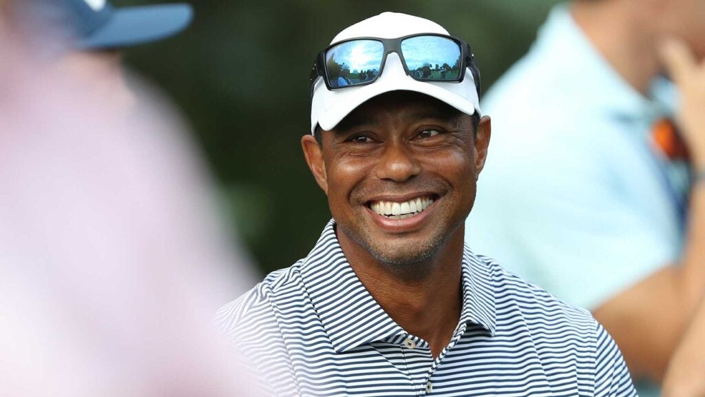 tiger woods smiles with sunglasses on hat and striped shirt at U.S. Junior Amateur.