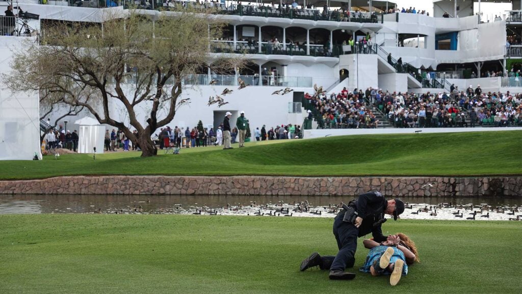 a police officer arrests a fan in front of the 16th hole at the WM Phoenix Open.