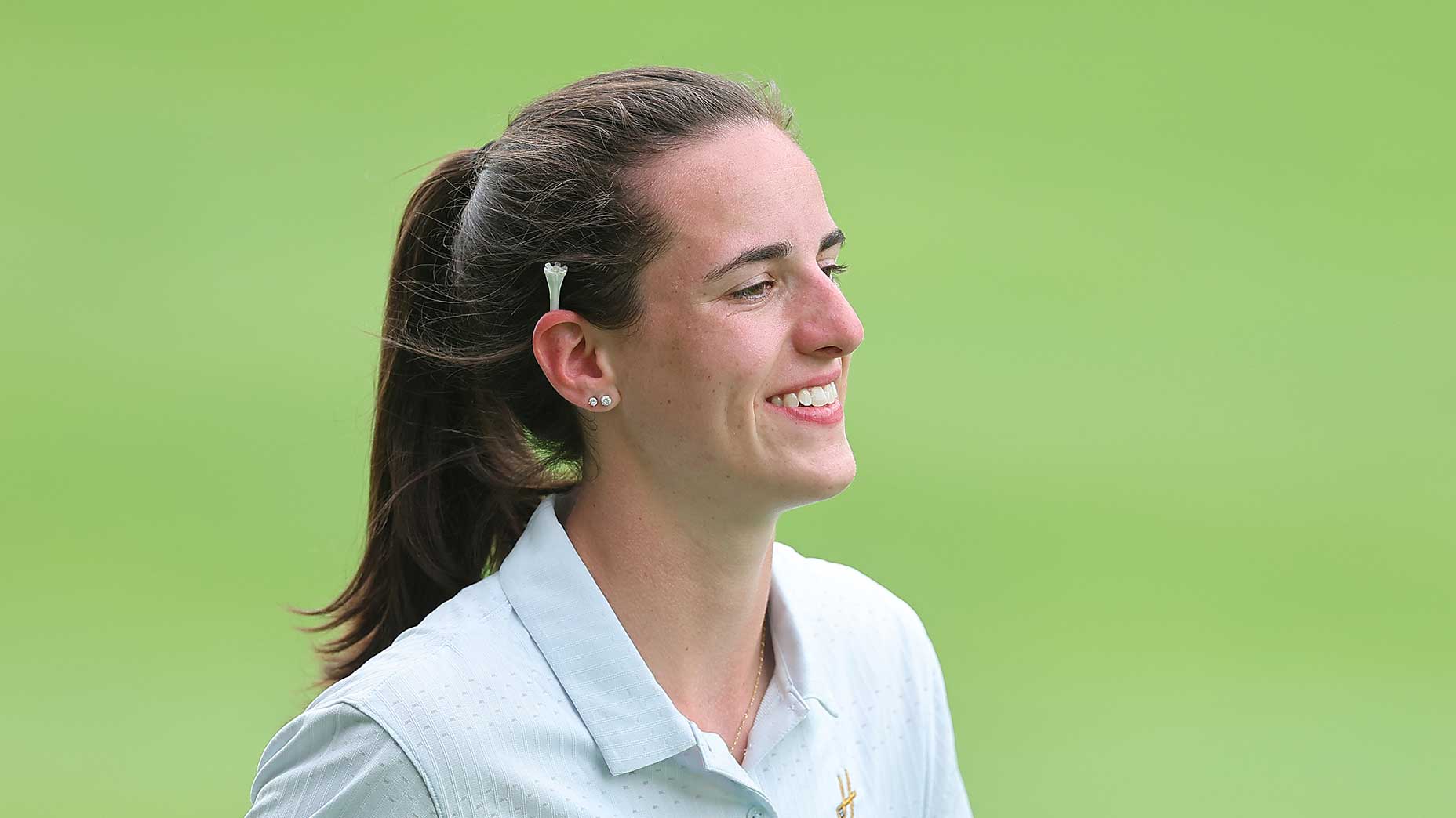 caitlin clark smiles with a tee behind her ear in a white shirt at the John Deere