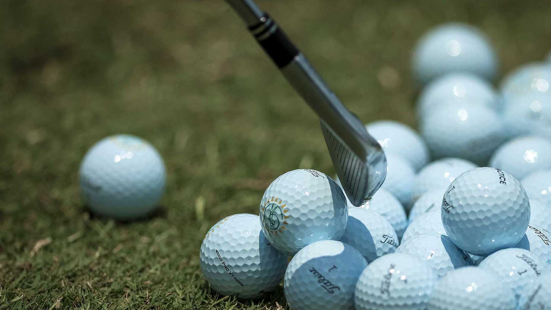 Pile of golf balls on driving range.