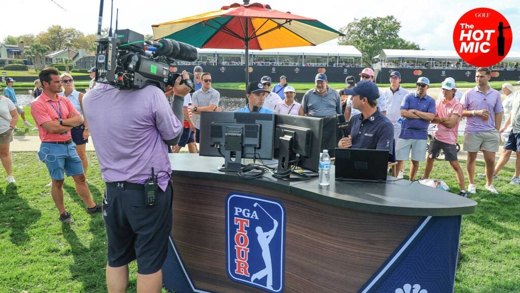 golf channel hosts sit at desk with the PGA Tour logo underneath it and cameras shooting video