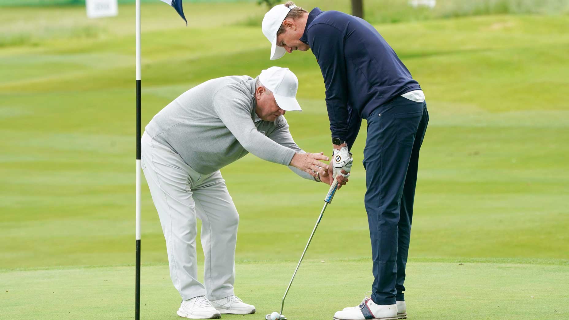 golf teacher helps student on the putting green