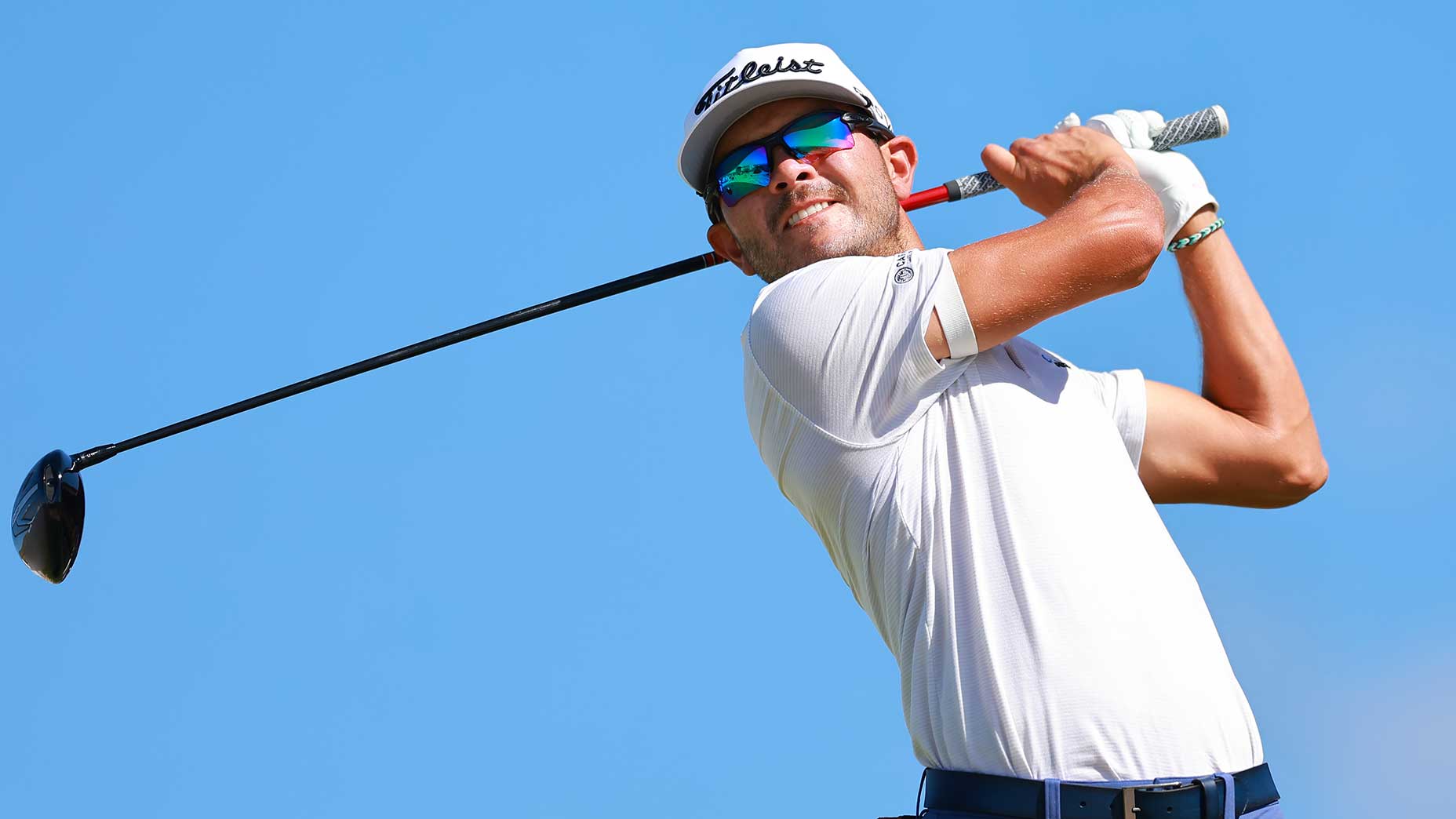 raul pereda swings a driver wearing a white shirt and hat at the Butterfield Bermuda Championship.