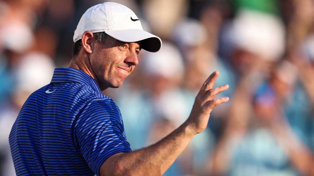 rory mcilroy waves to crowd at DP World Tour Championship in blue shirt and white hat