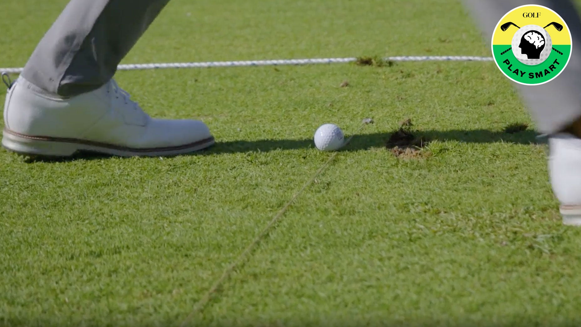 golf ball on ground with piece of string running perpendicular to it