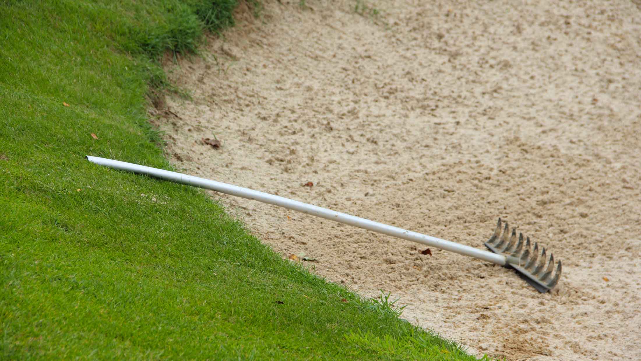 A rake left on the edge of a bunker