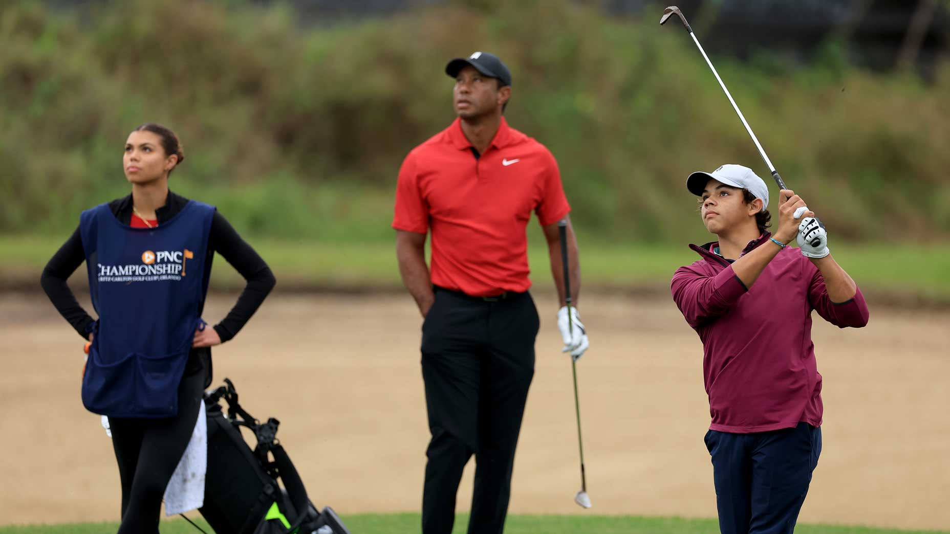 Charlie Woods plays his second shot on the 15th hole watched by his father Tiger Woods and his sister Sam Woods during the final round of the PNC Championship at The Ritz-Carlton Golf Club.