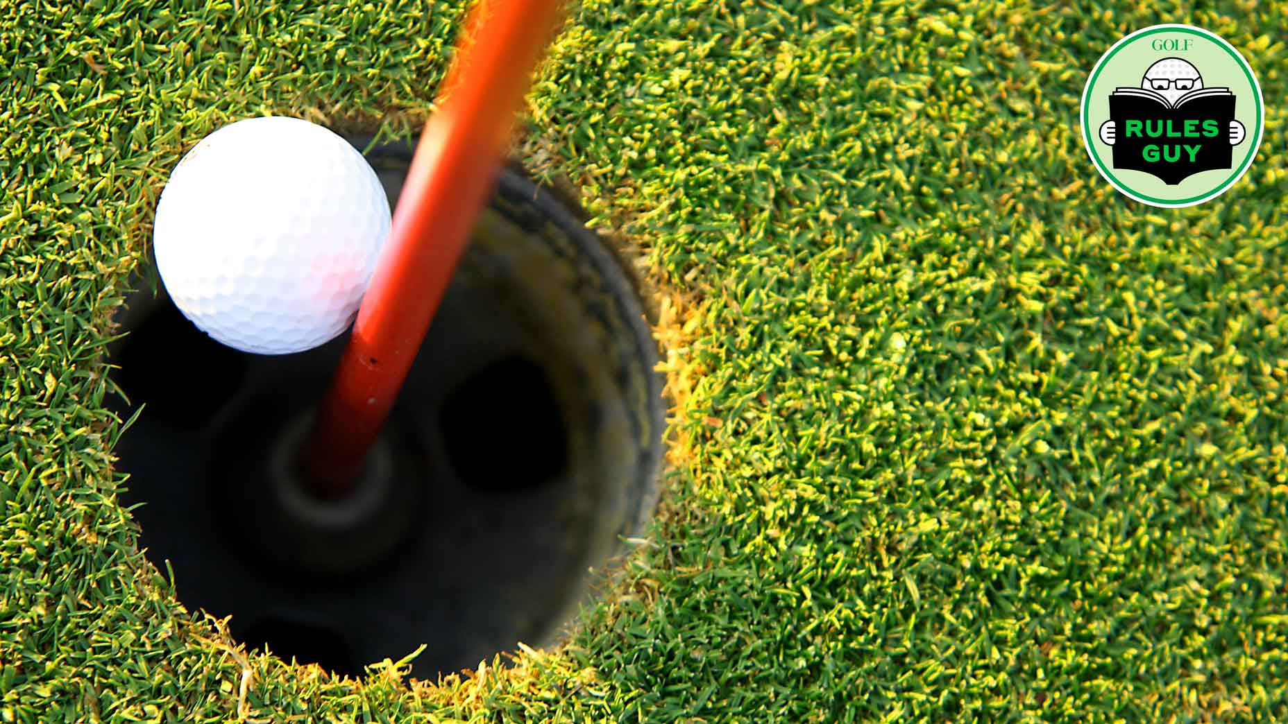 Golf ball resting against pin and about to drop into hole