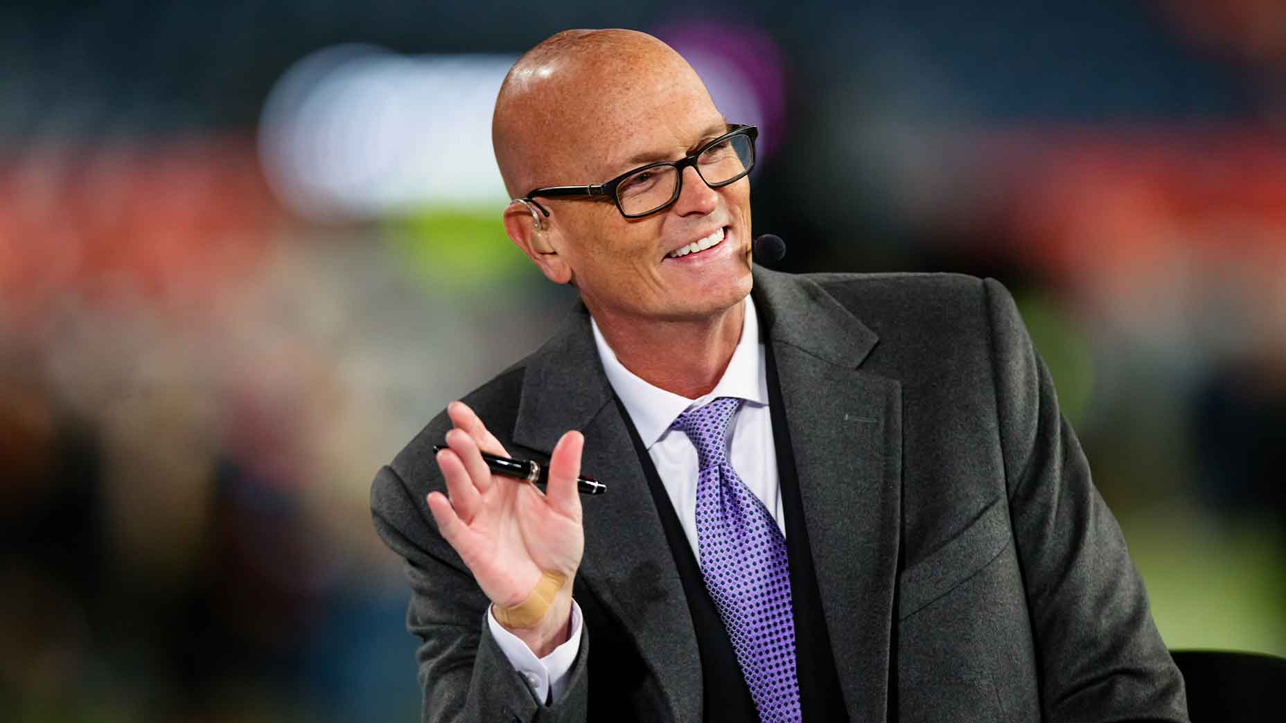 scott van pelt smiles on set for ESPN monday night football in a black jacket and purple tie