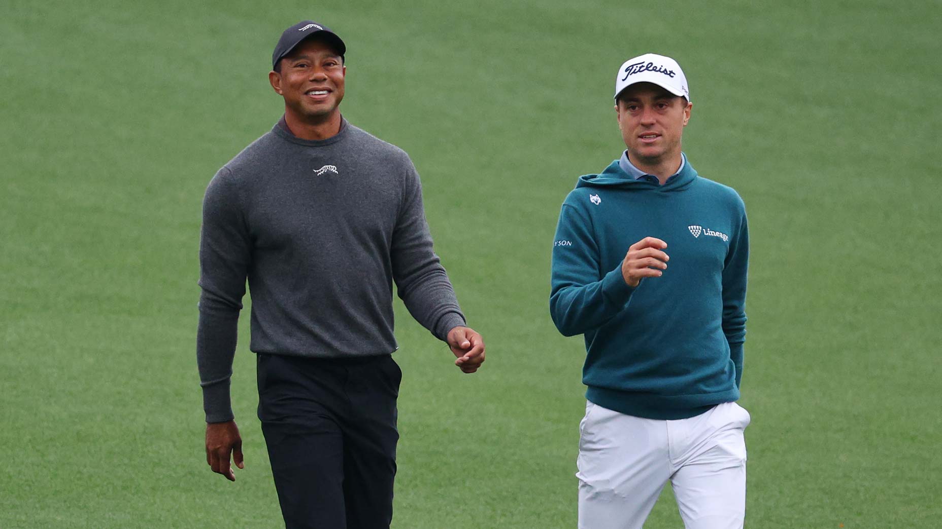 Tiger Woods e Justin Thomas caminham pelo primeiro fairway durante uma rodada de treinos antes do Torneio Masters de 2024 no Augusta National Golf Club.