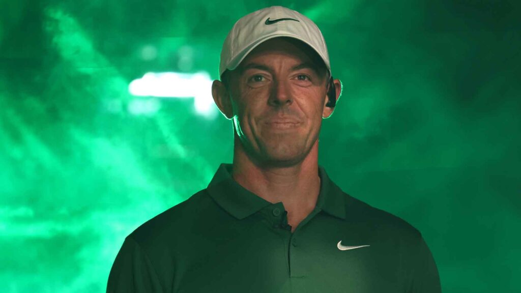 rory mcilroy smiles in green fog machine light at TGL broadcast