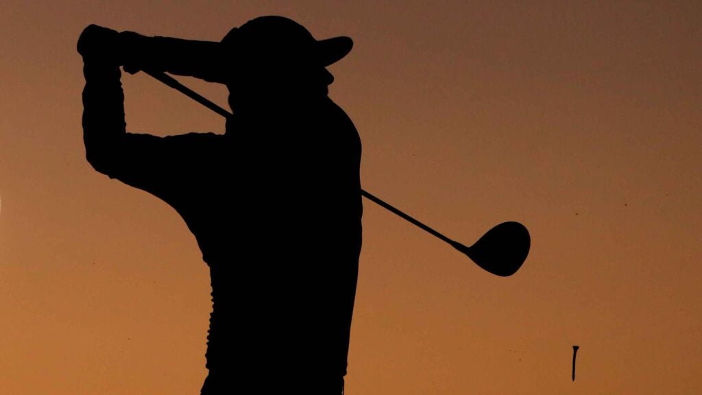 golfer hitting shot on the driving range as the sun rises