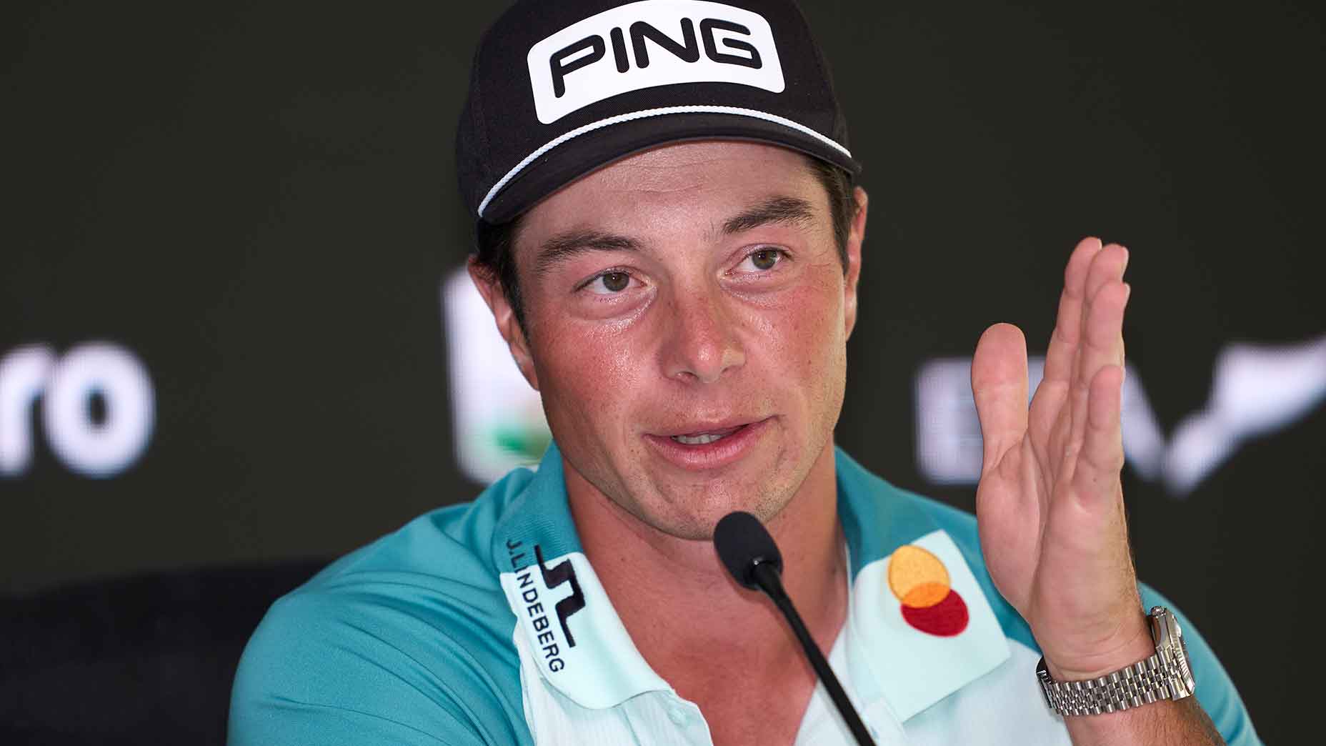 viktor hovland points straight forward in teal and white shirt at the Dubai Desert Classic