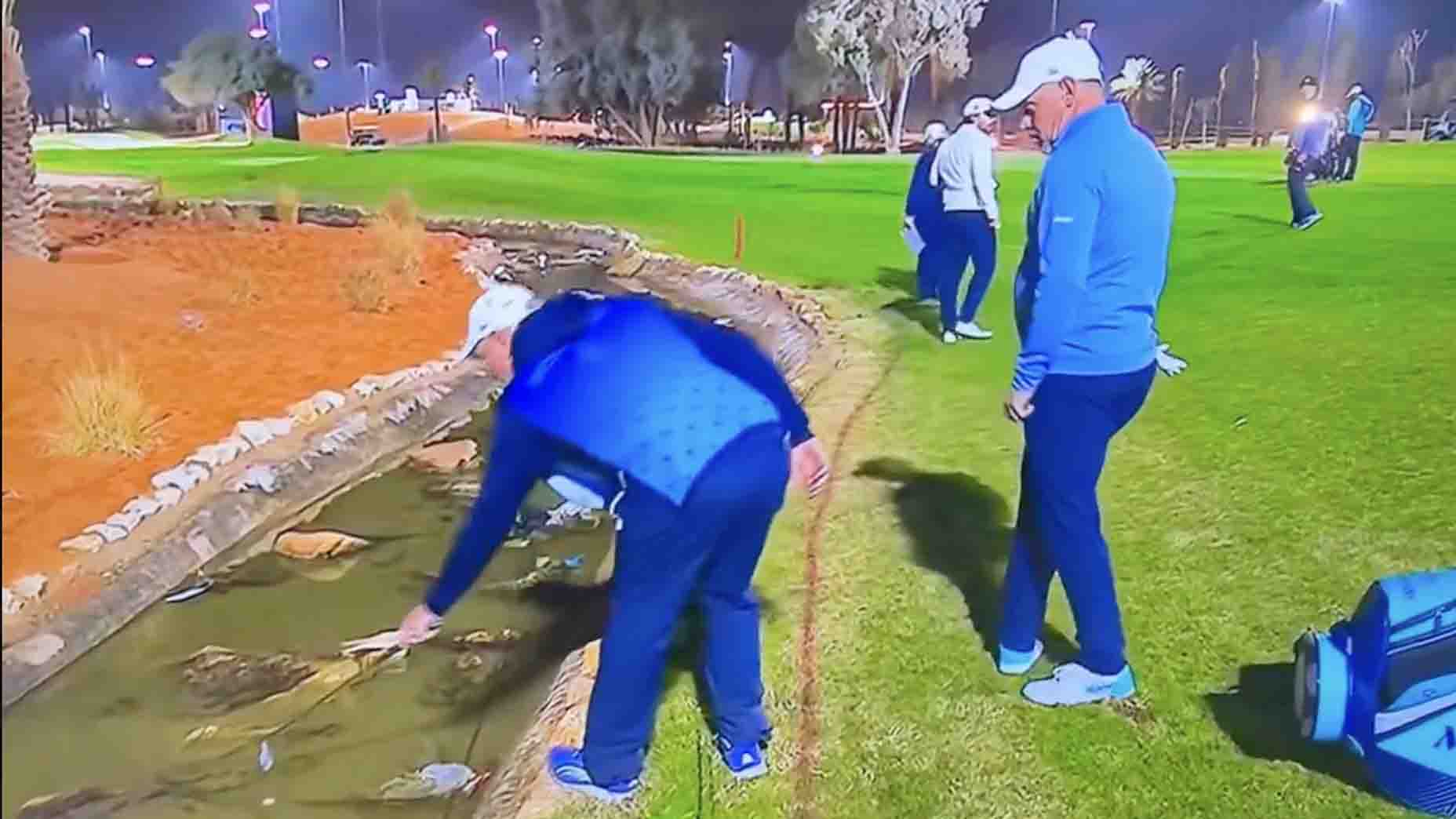 Lee Westwood and his caddie retriever his ball in the hazard during Round 2 of LIV Riyadh.