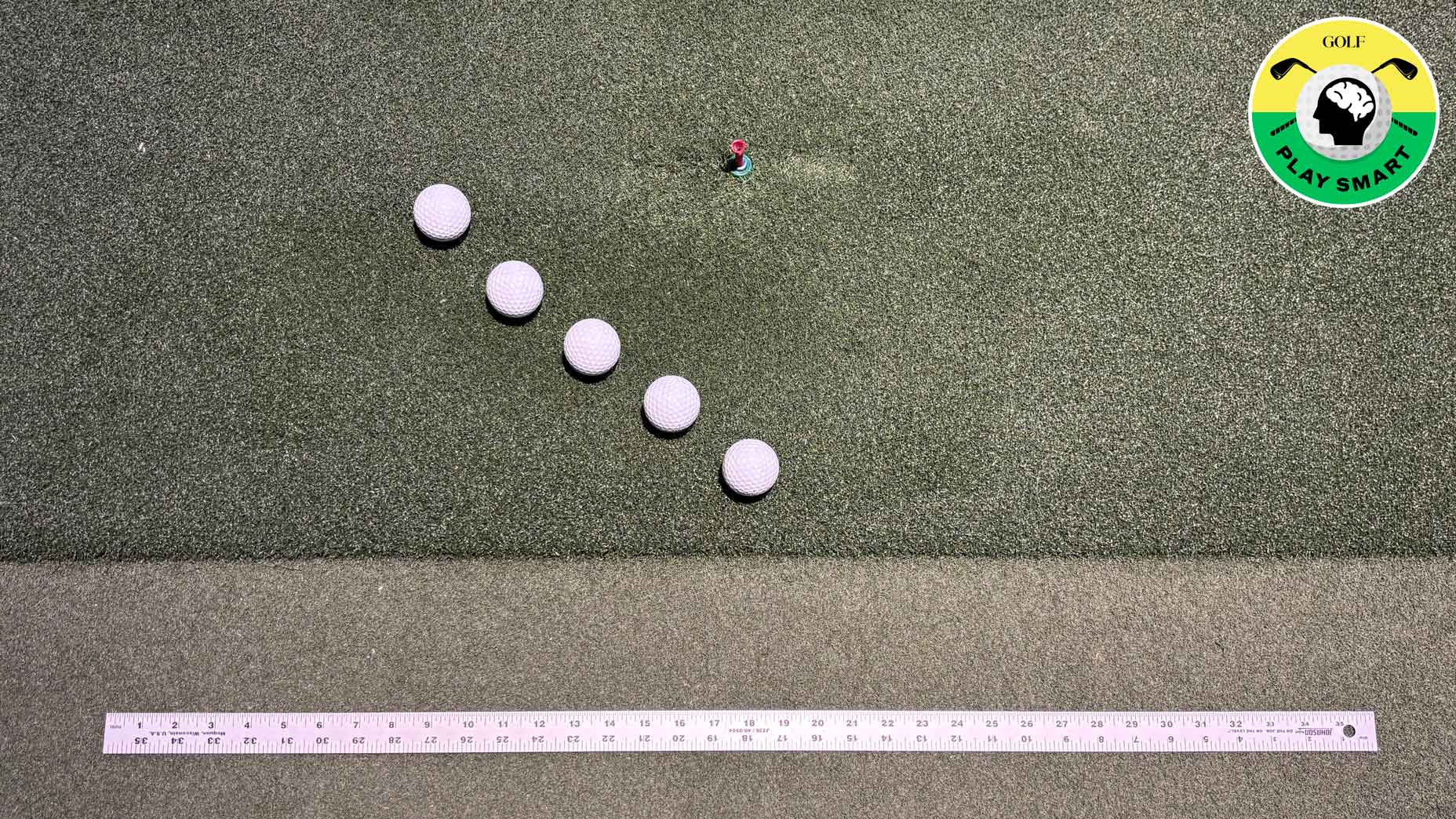 five golf balls on the ground with a yard stick beneath