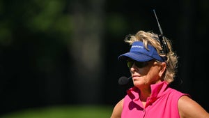 dottie pepper stares in blue hat and pink shirt at at the PGA Championship with headset on.