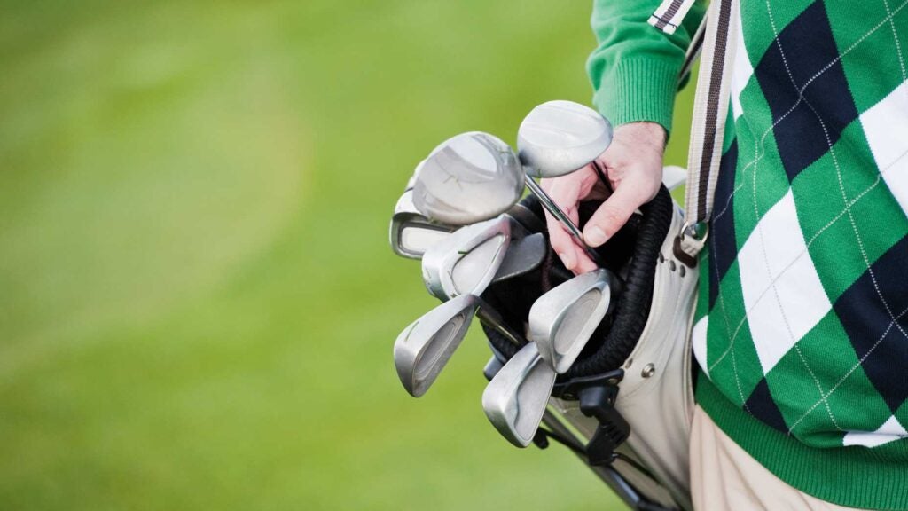 A man carries a golf bag.