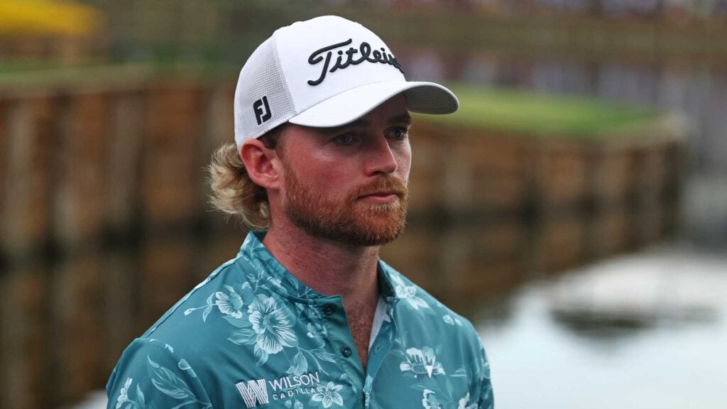 danny walker stands at island green 17th at the players championship in blue shirt and white hat