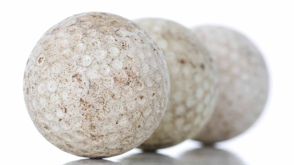 Three dirty golf balls arranged in a line on a white background.