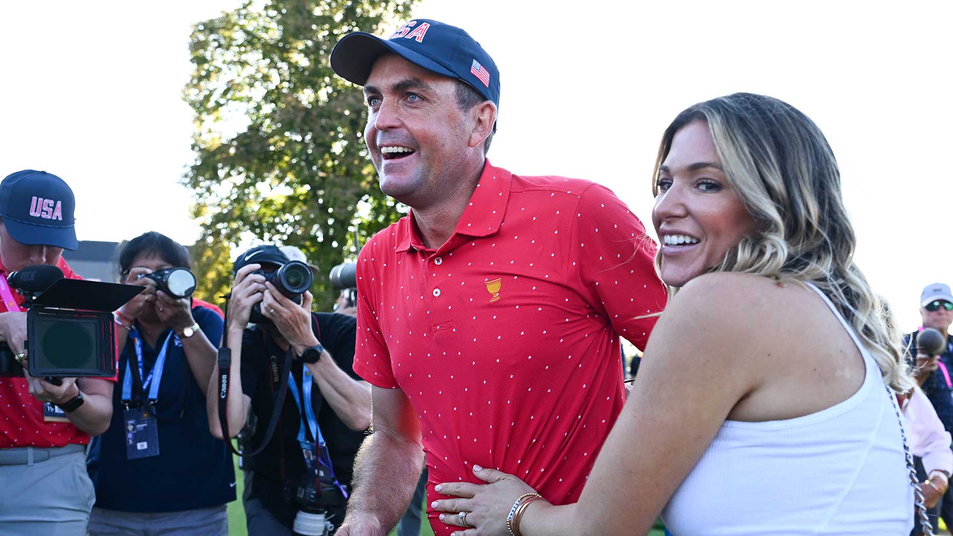 keegan bradley smiles in red shirt and blue hat at the presidents cup in montreal