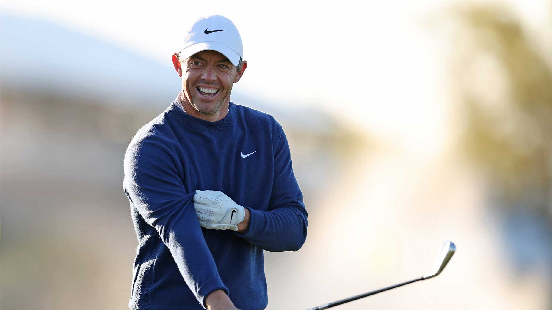 rory mcilroy smiles at the players championship in navy sweater and white hat