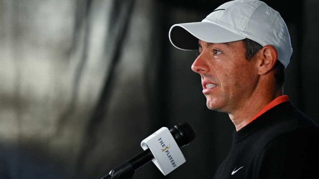 rory mcilroy speaks into camera and microphone in white hat and black sweatshirt at the Players Championship