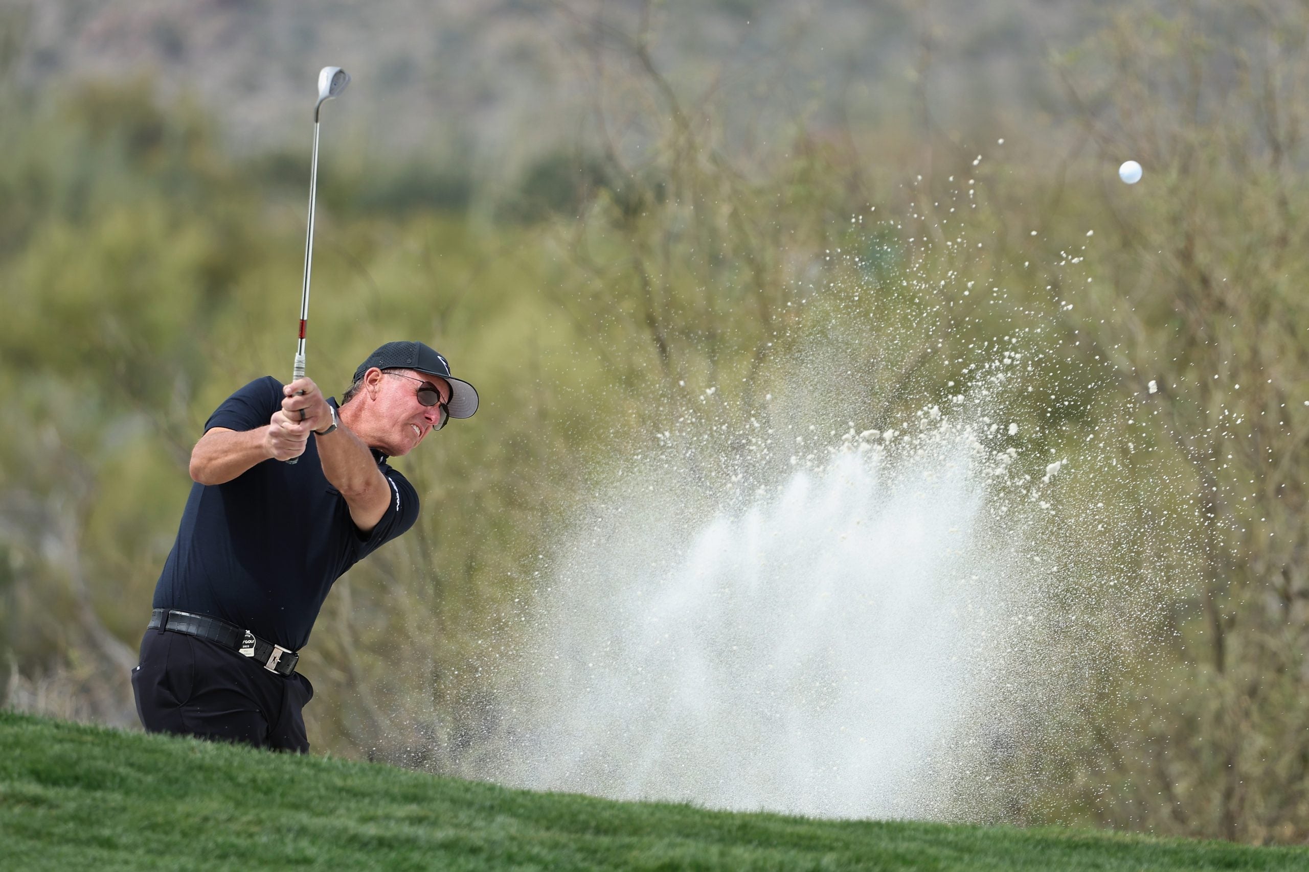 Phil Mickelson hits a wedge from a bunker