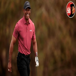 tiger woods smiles walking down the fairway
