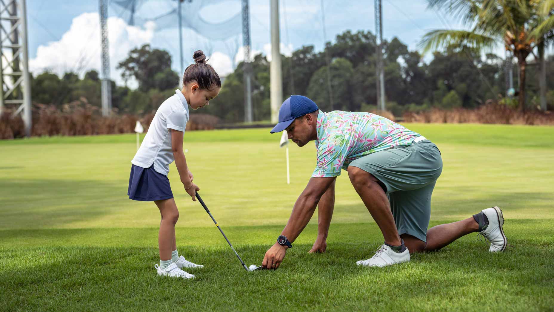 golf parent helps daughter tee up golf ball