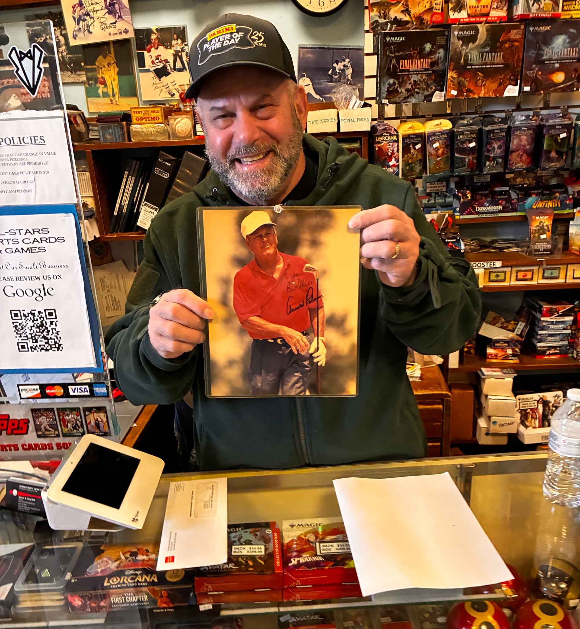 warren wolk at his store holding a signed photo of arnold palmer