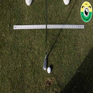 yardstick lays on the ground next to golf ball and golf club