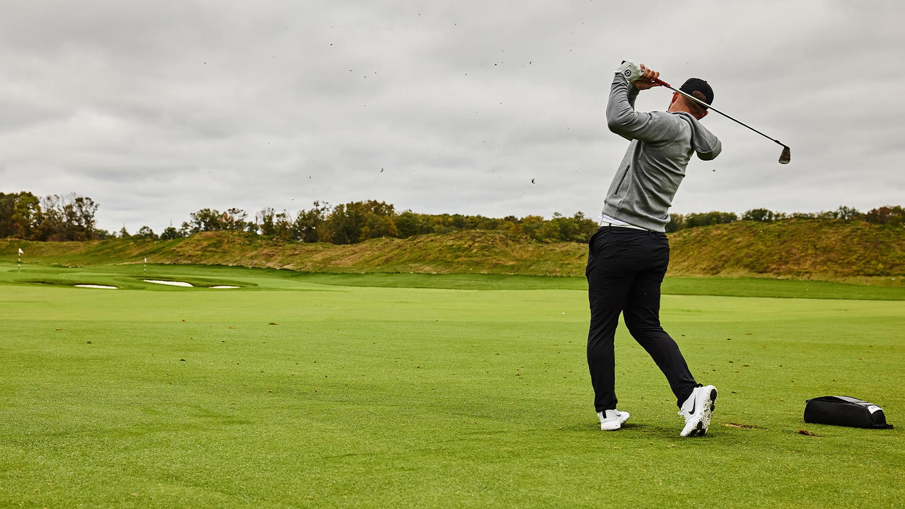 mike trout swings golf club at Trout National in grey sweatshirt