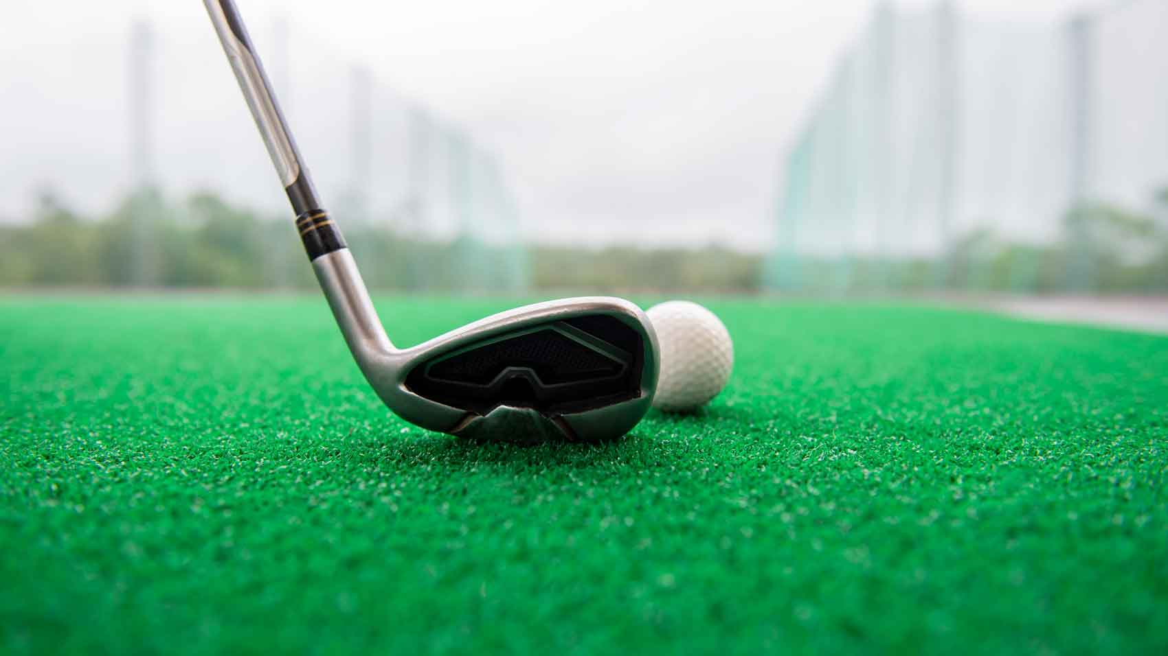 golf club and golf ball on green hitting mat