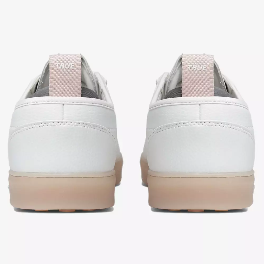 Back view of a pair of white low-top sneakers with light beige pull tabs labeled TRUE and light brown rubber soles, shown against a plain white background&mdash;the perfect blend of style and comfort for the best women's golf shoes 2026.