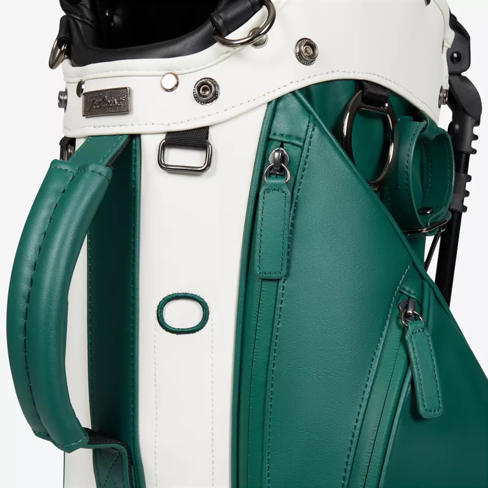 Close-up of a green and white golf bag featuring metal hardware, zippers, and handles, with visible stitching and textured leather-like material&mdash;showcasing features you&rsquo;ll find in the best golf bags 2026.