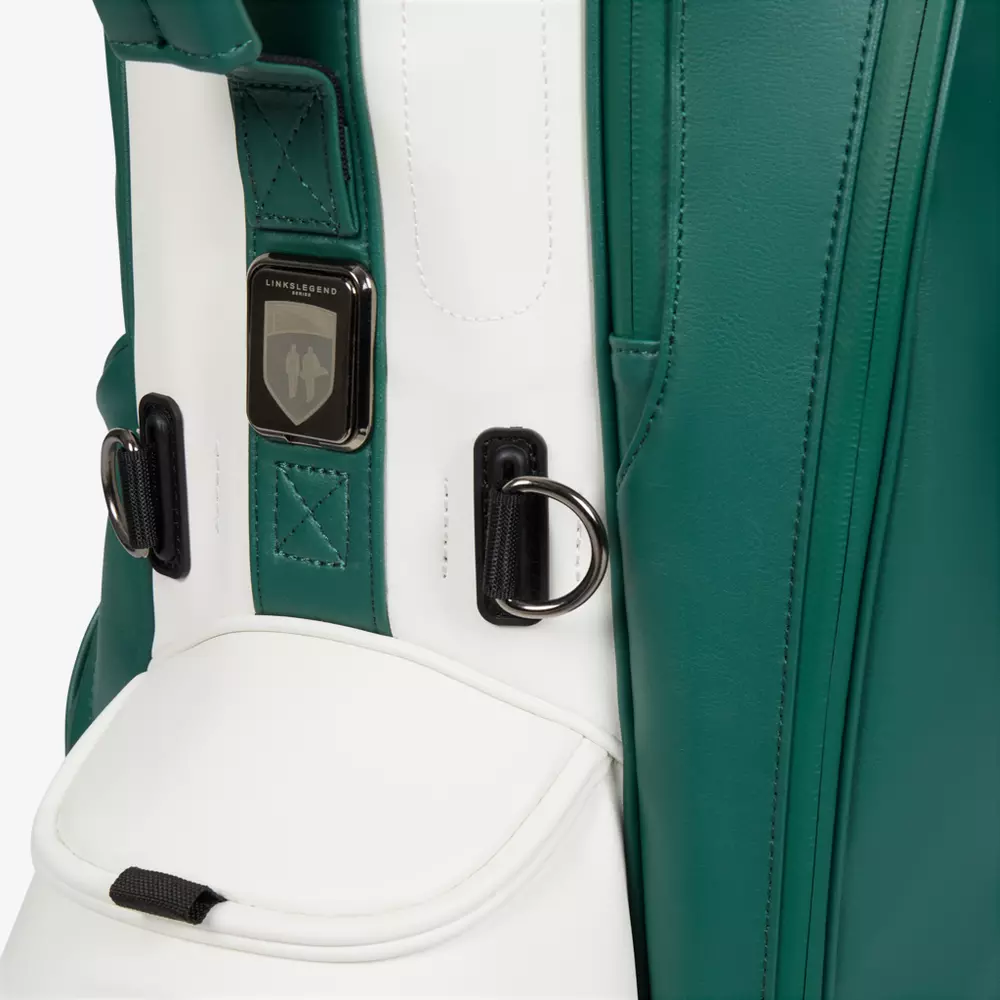 Close-up of a green and white golf bag, featuring metal rings and a black-and-silver Linksmaster logo badge above a pocket with a black pull tab&mdash;an example of the best golf bags 2026 has to offer.