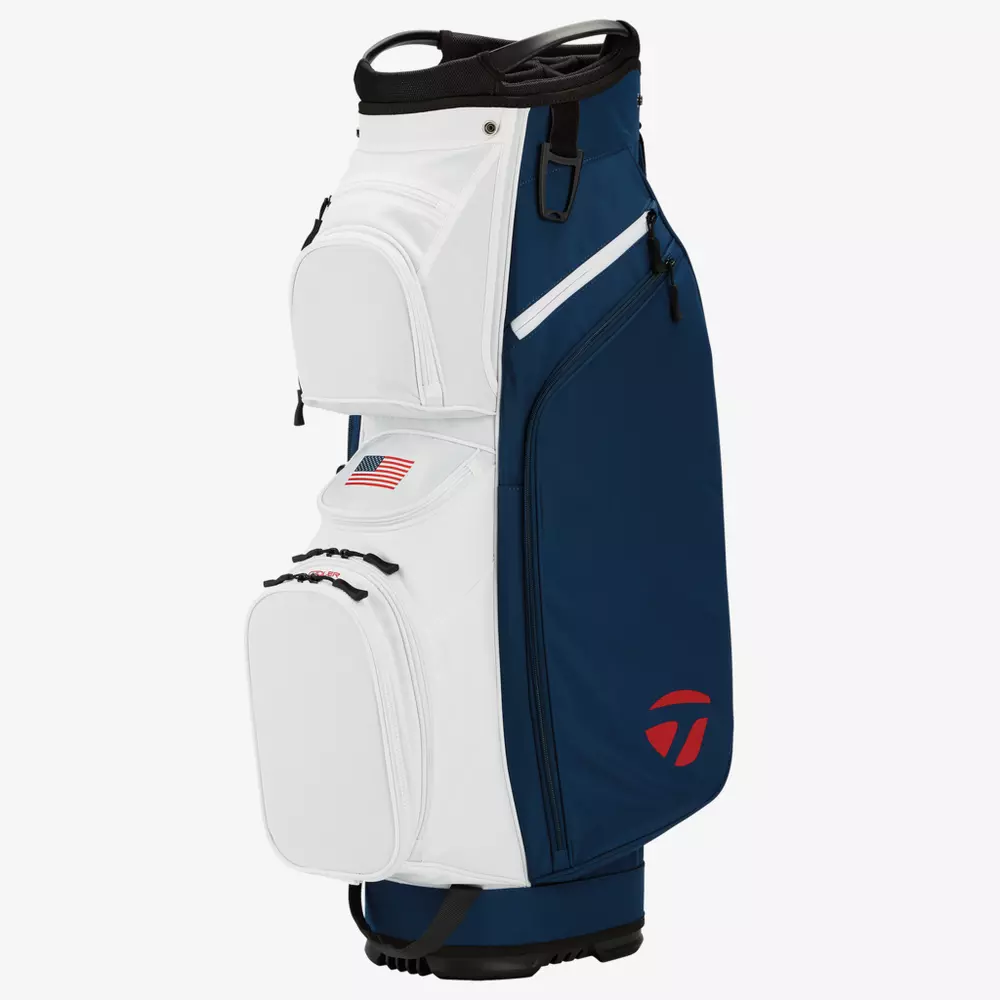 A golf bag with a white front, blue sides, several zippered pockets, an American flag patch, and a red logo near the base&mdash;an ideal choice for those seeking one of the best golf bags 2026&mdash;stands upright against a plain white background.