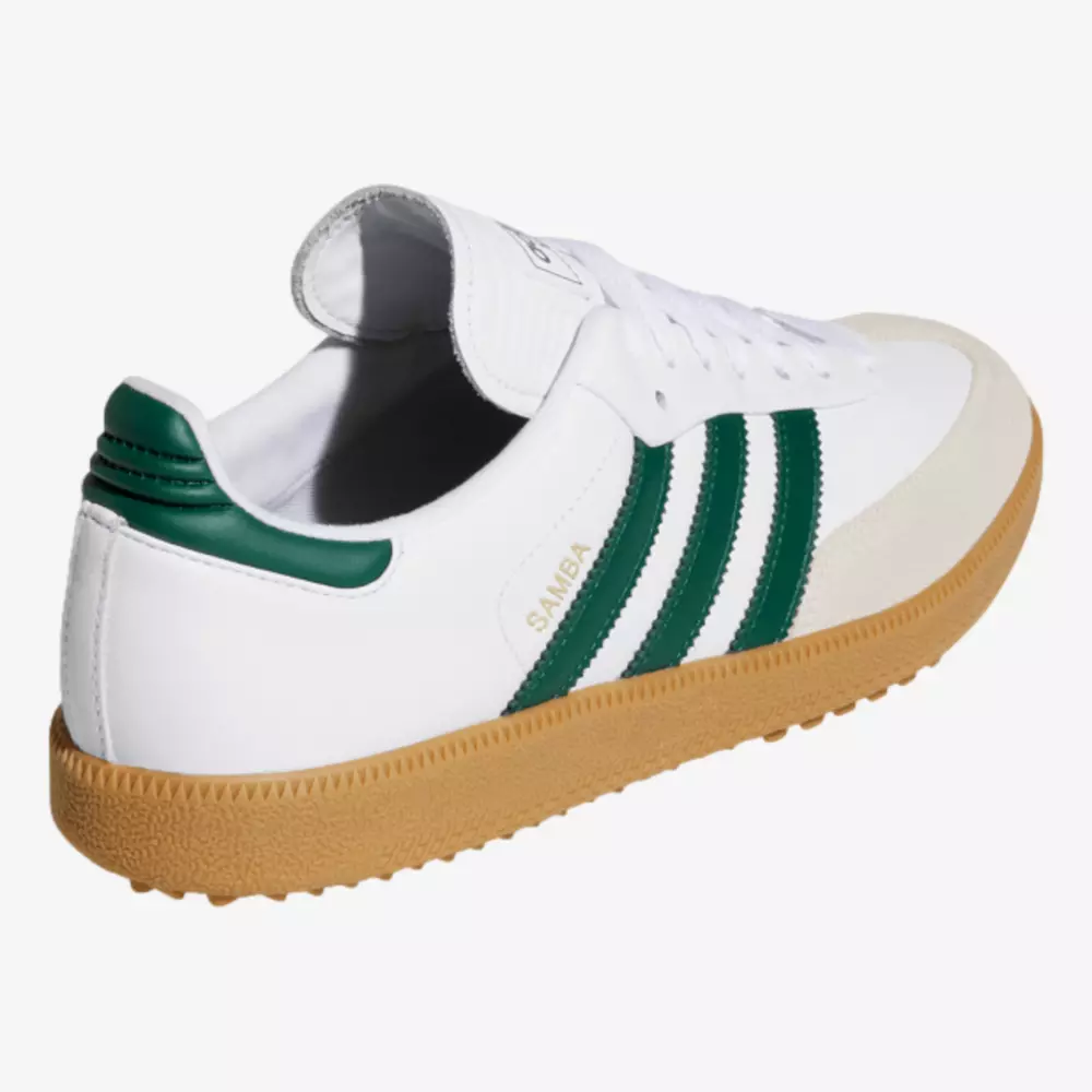 A white Adidas Samba sneaker, inspired by the best women's golf shoes 2026, features green stripes, a green heel detail, tan gum sole, and SAMBA in gold on the side, shown at an angle from the back.