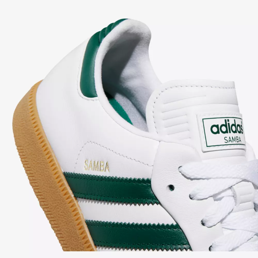 Close-up of a classic adidas Samba sneaker featuring white leather, green stripes and heel detail, gold SAMBA lettering, a gum sole, and white laces. A stylish choice inspired by the best women's golf shoes 2026. The adidas logo tag is visible on the tongue.
